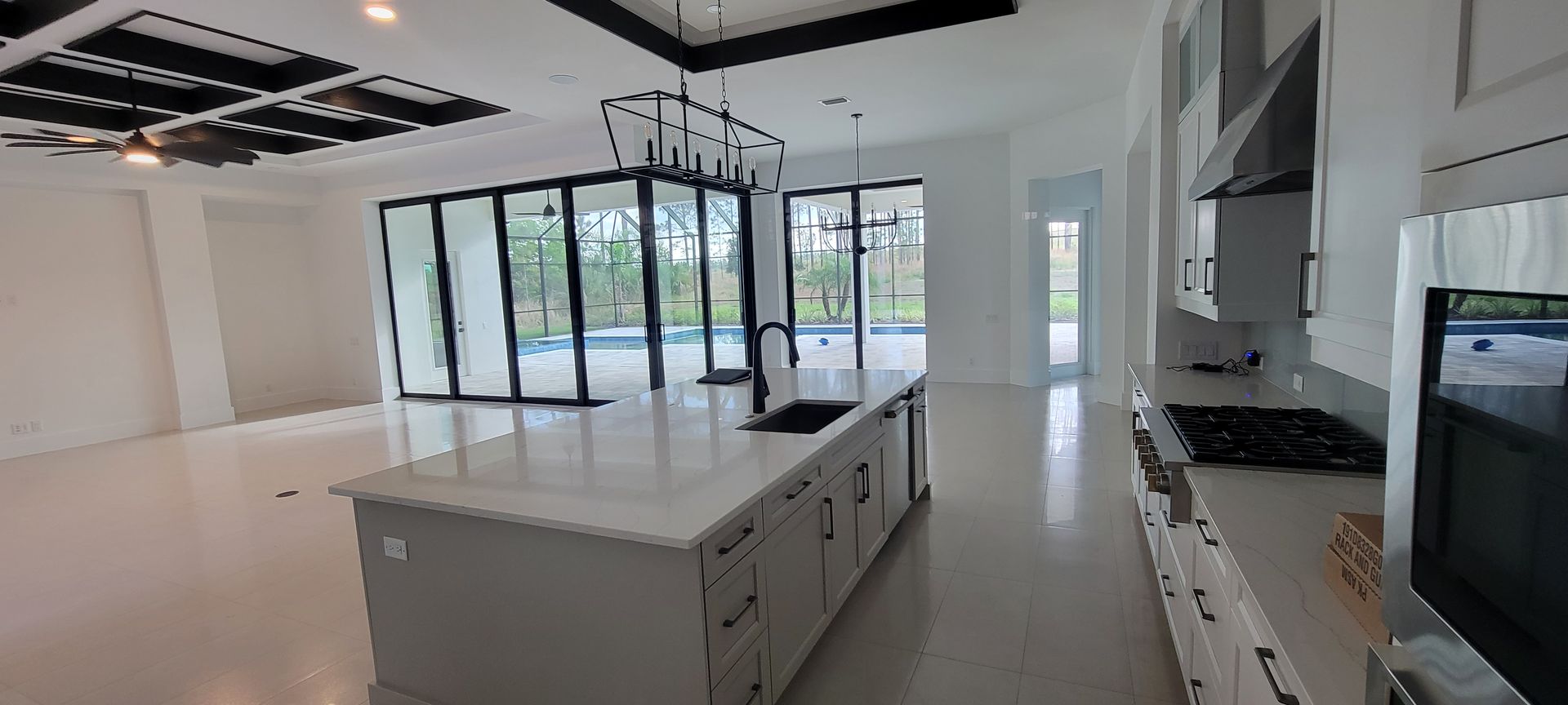 Spacious, modern kitchen with large island, glass doors leading to the outside and a cooktop.