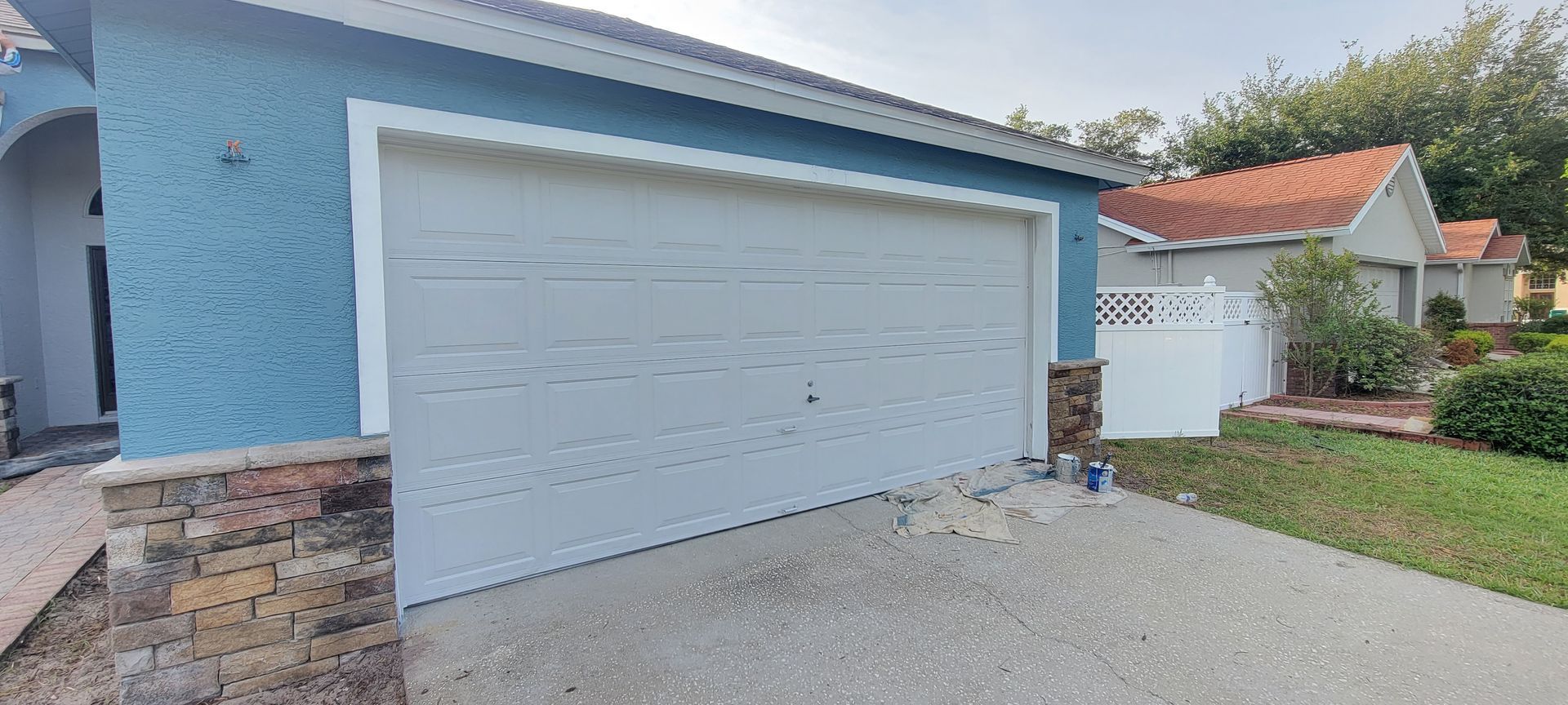A blue house with a white garage door is for sale.