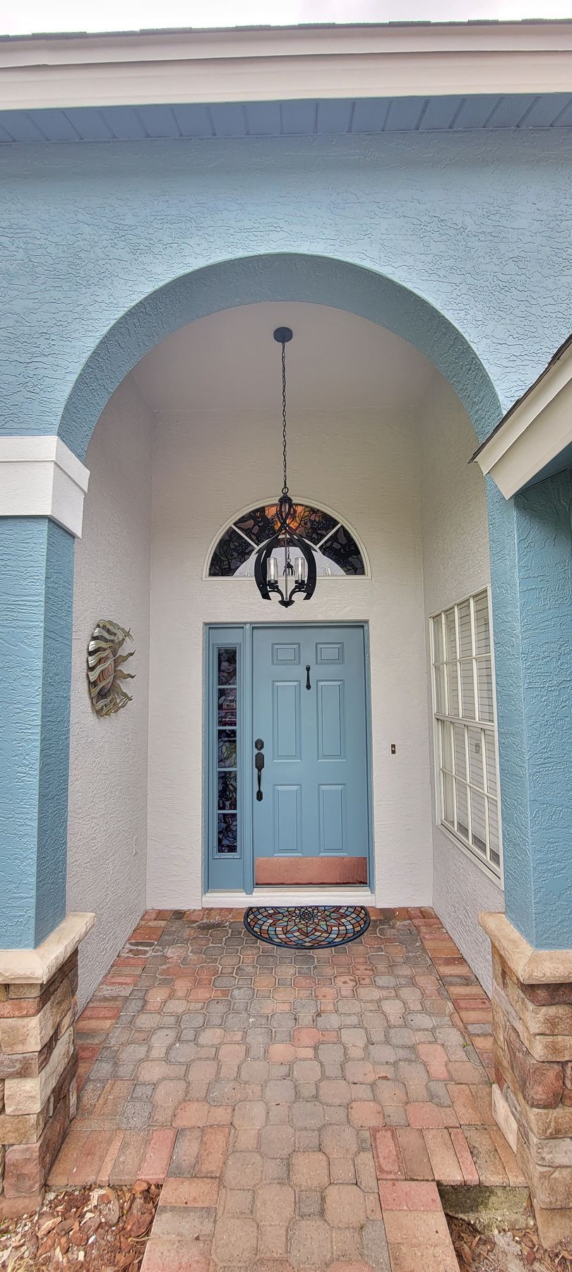 The front door of a house with a blue door and a chandelier hanging from the ceiling.