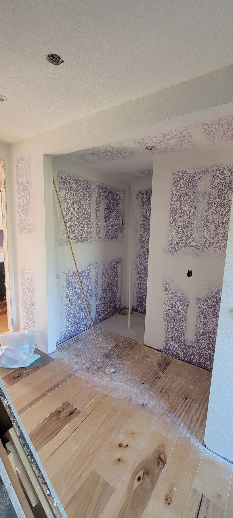 A room with a wooden floor and purple wallpaper on the walls.