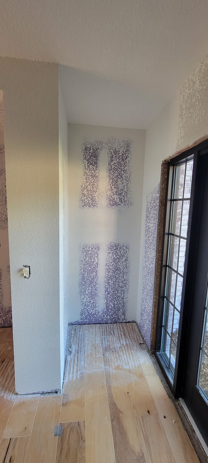 A hallway with a sliding glass door and a wooden floor.