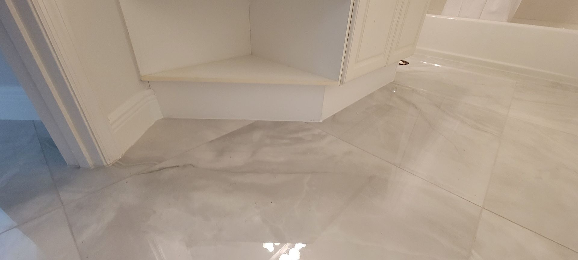 A bathroom with a tiled floor and white cabinets.