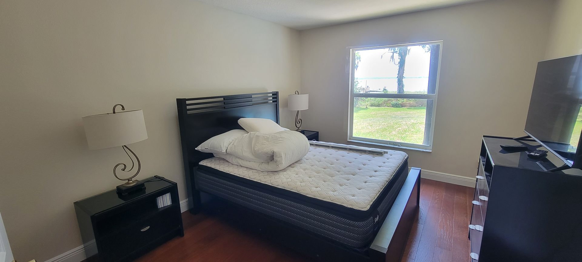 A bedroom with a bed , nightstand , lamp and television.