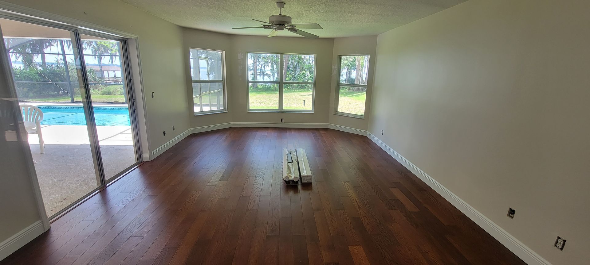 An empty living room with hardwood floors and a ceiling fan.