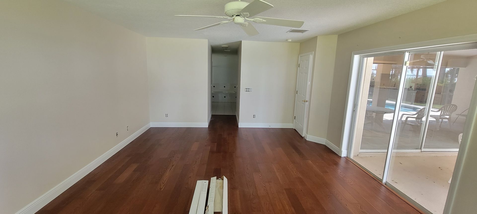 An empty living room with hardwood floors and a ceiling fan.