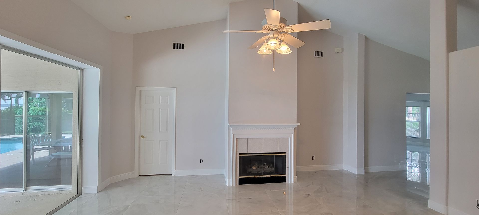 An empty living room with a fireplace and ceiling fan.