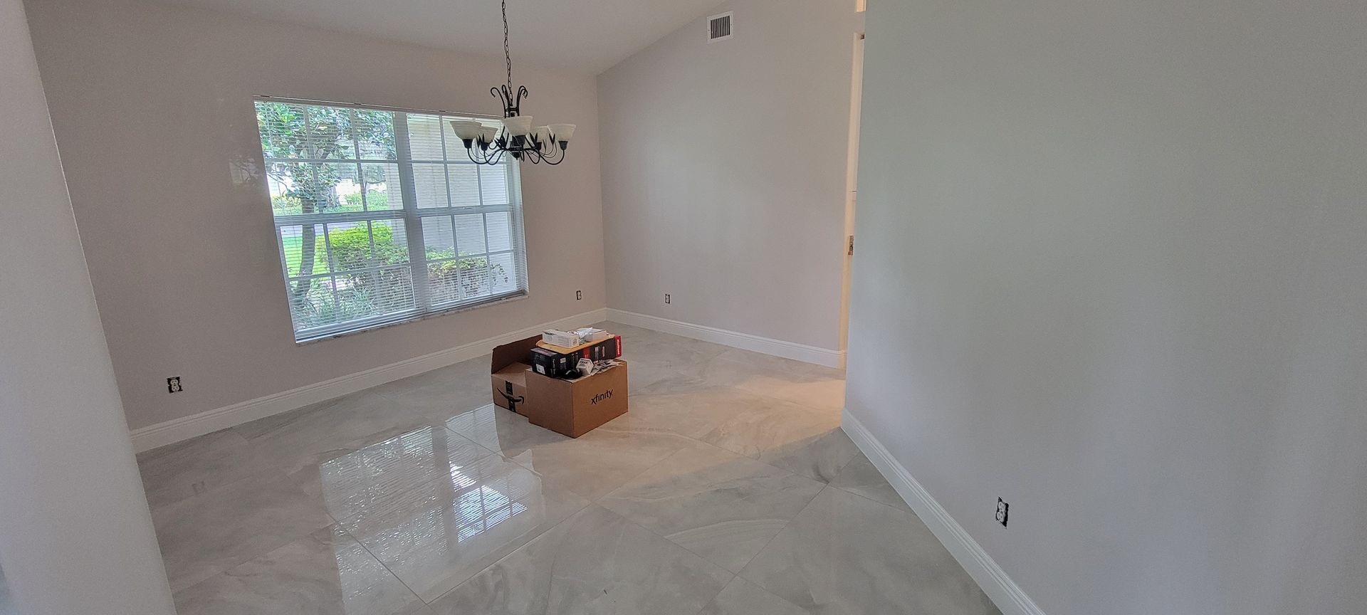 An empty living room with a box on the floor and a window.