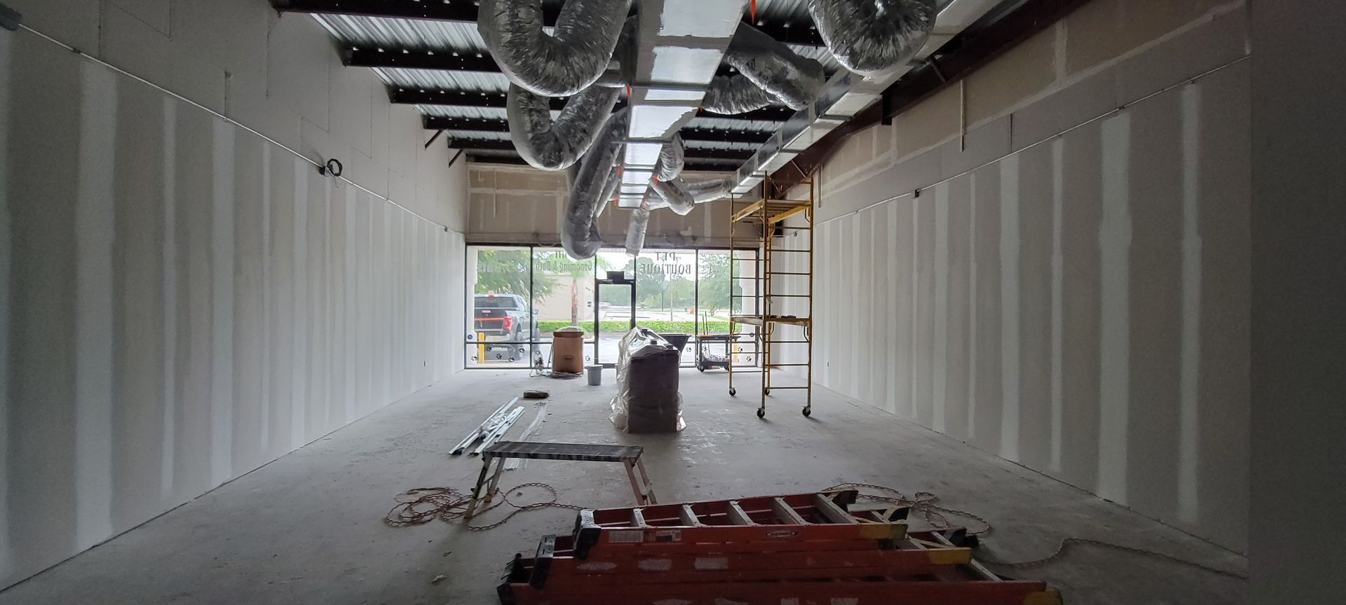A large empty room with a ladder in the middle of it.