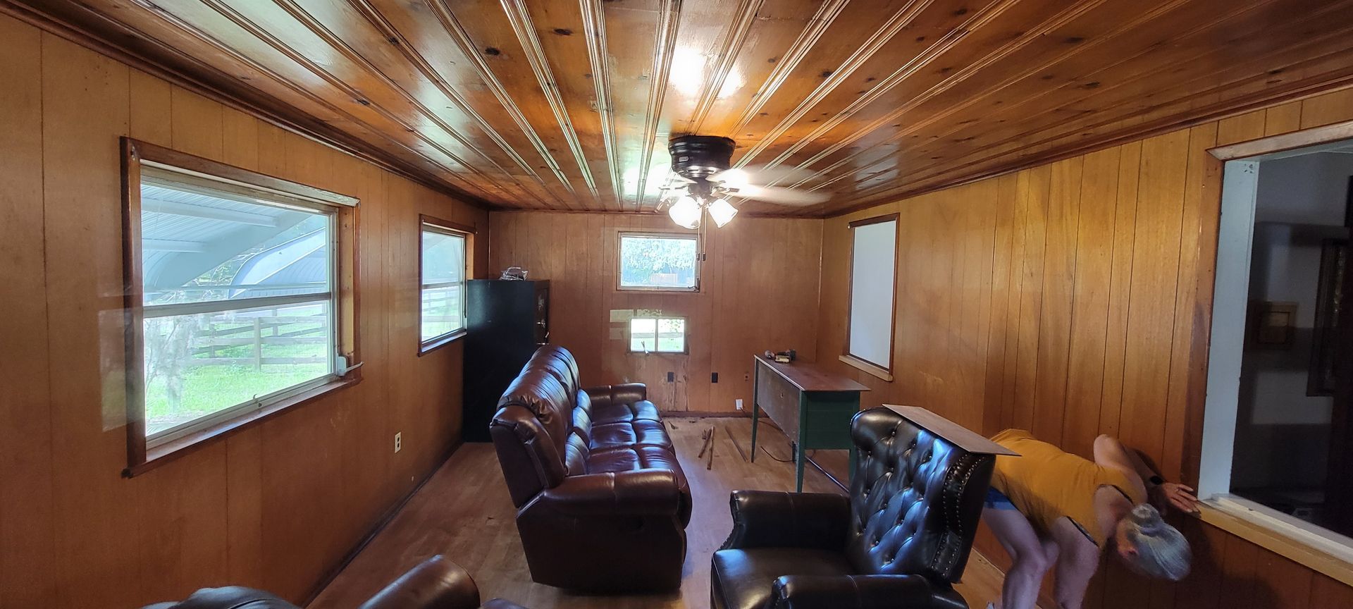 A living room with a couch and chairs and a ceiling fan.