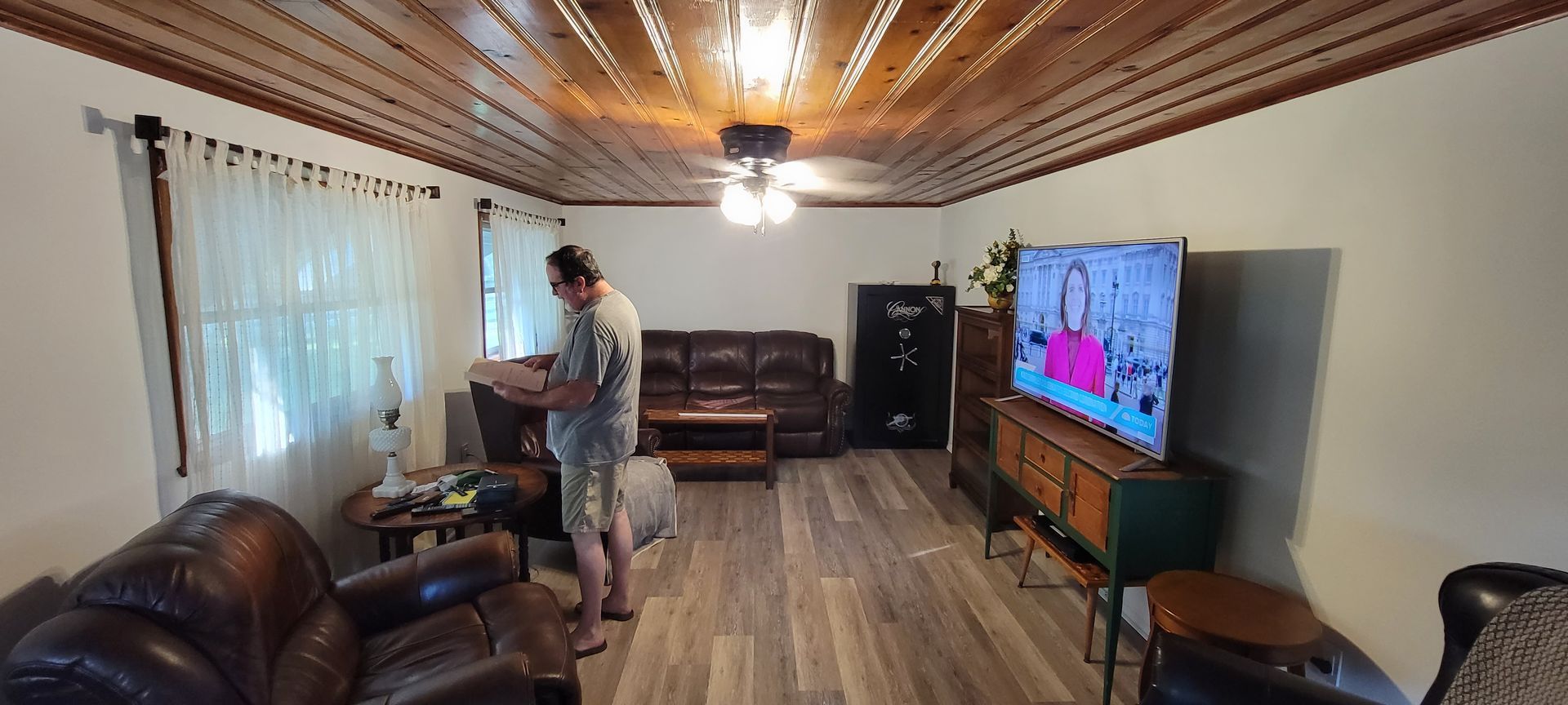 A man is standing in a living room in front of a television.