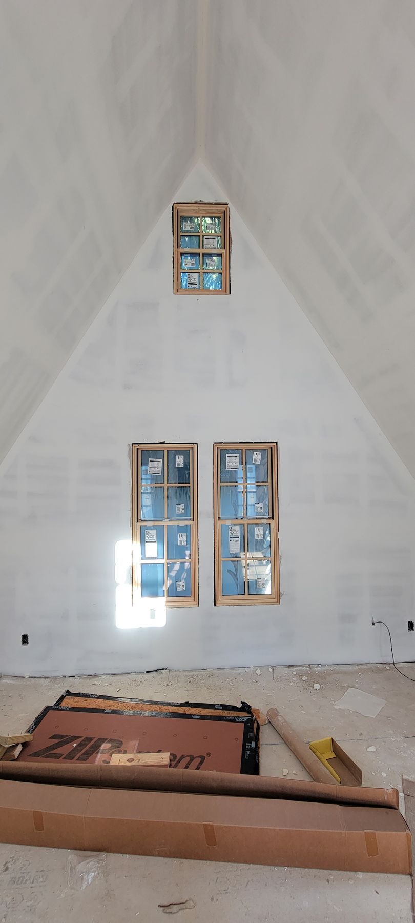 A room with a vaulted ceiling and two windows.