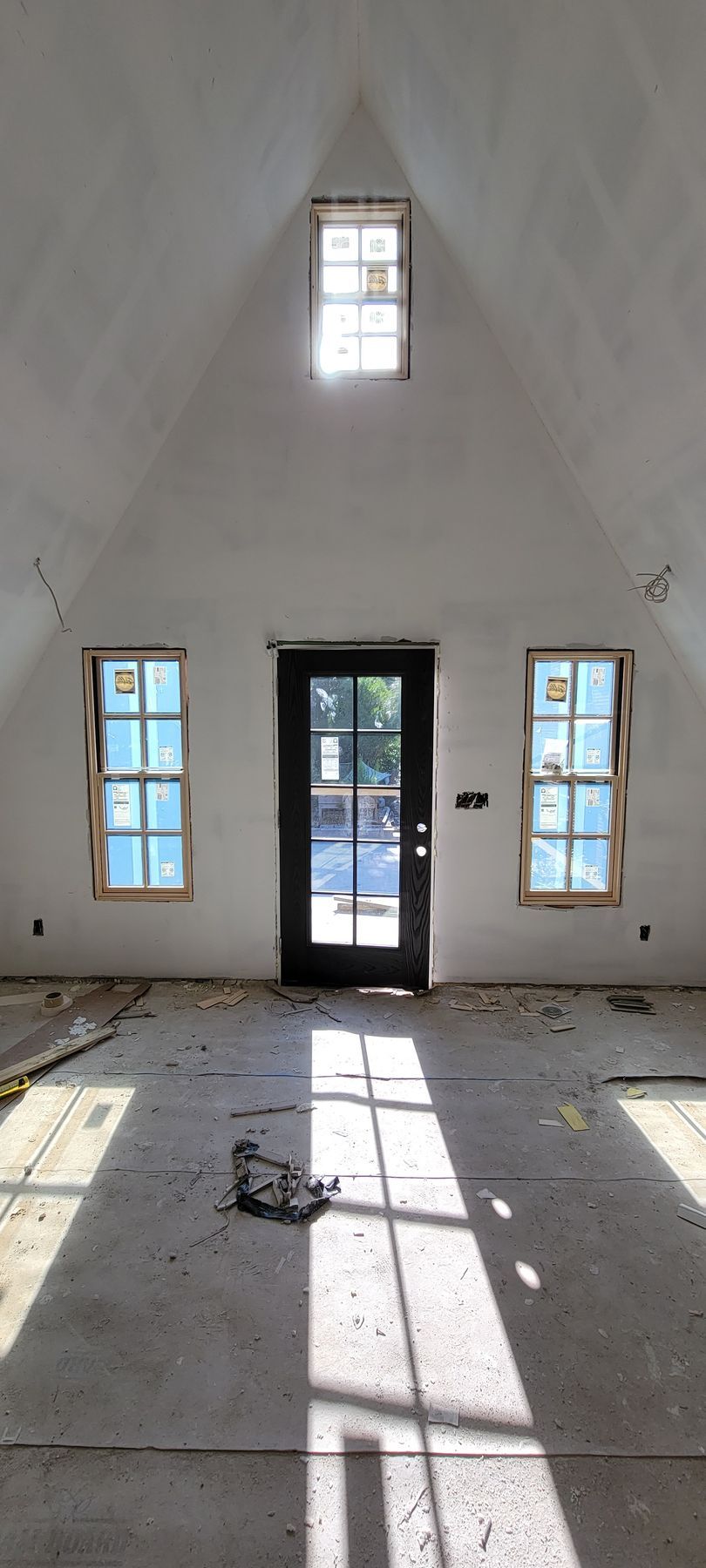 A large empty room with a door and three windows.