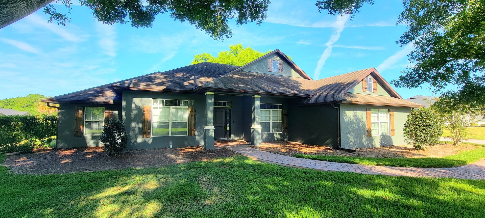 A large house with a lot of windows is sitting on top of a lush green lawn.