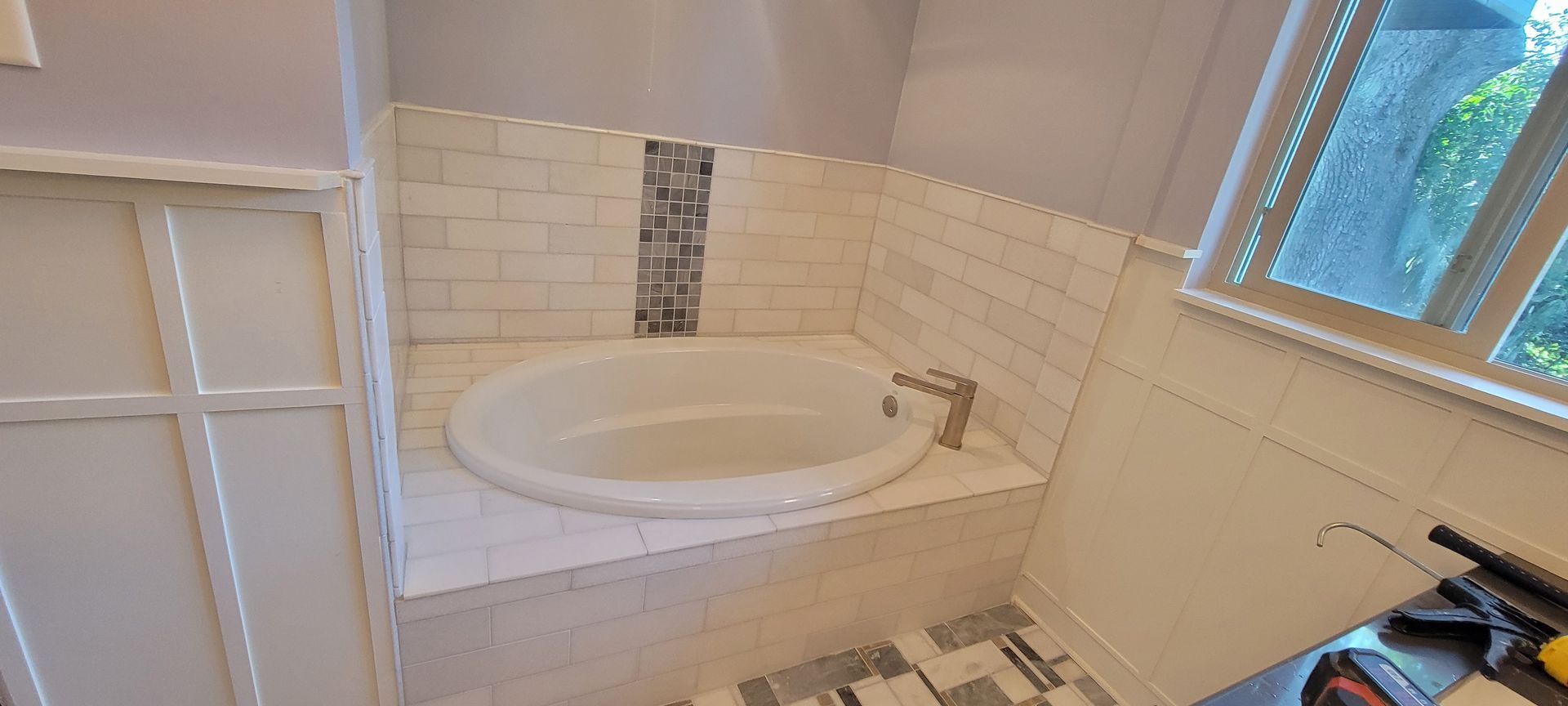 A bathroom with a bathtub and a window.