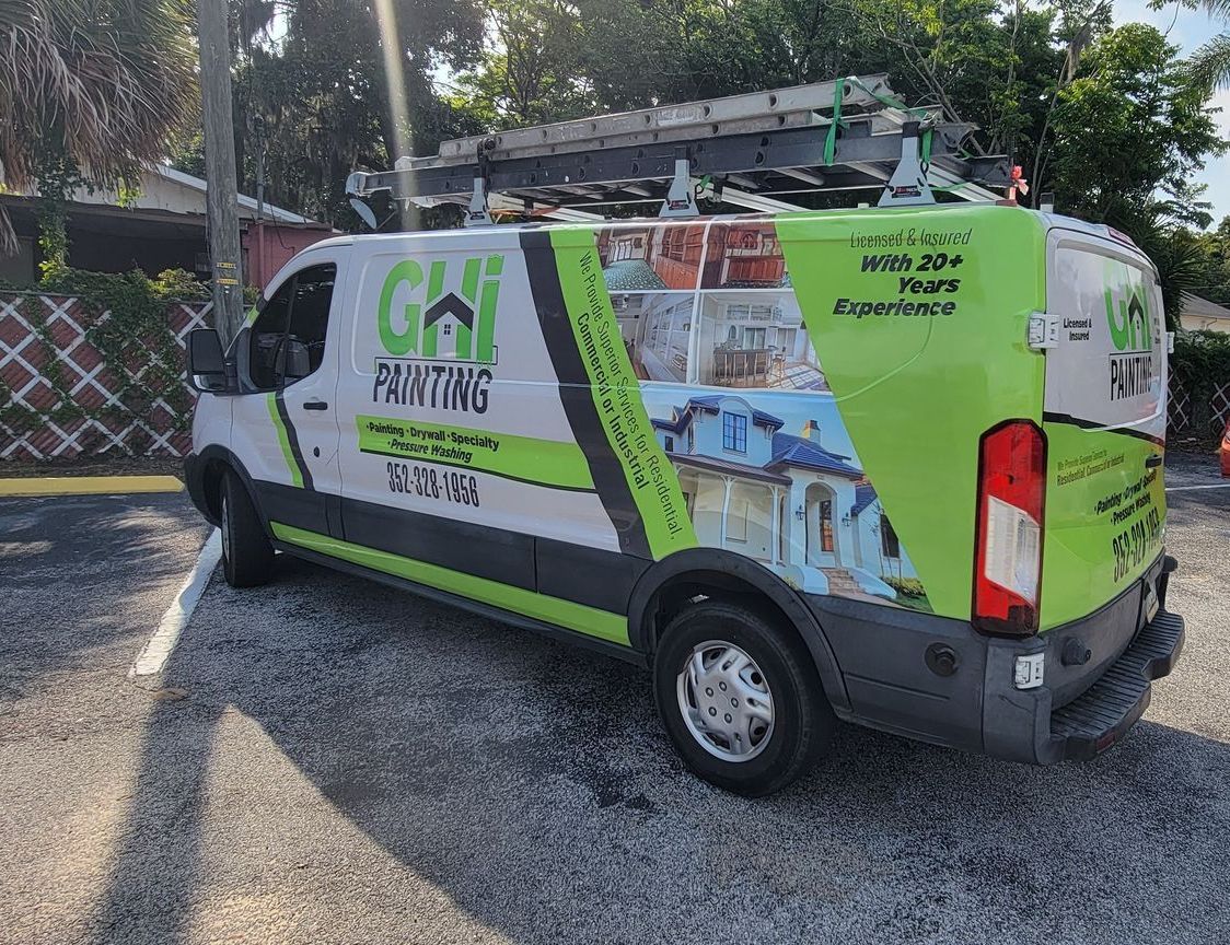 A blue house is sitting in the middle of a lush green field.