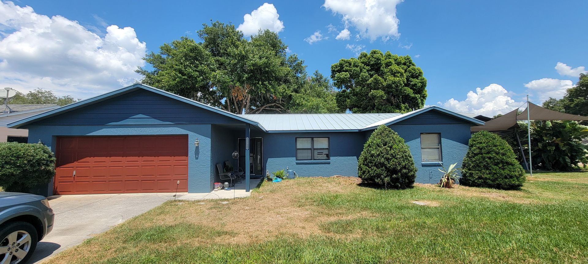 A blue house with a red garage door and a car parked in front of it.