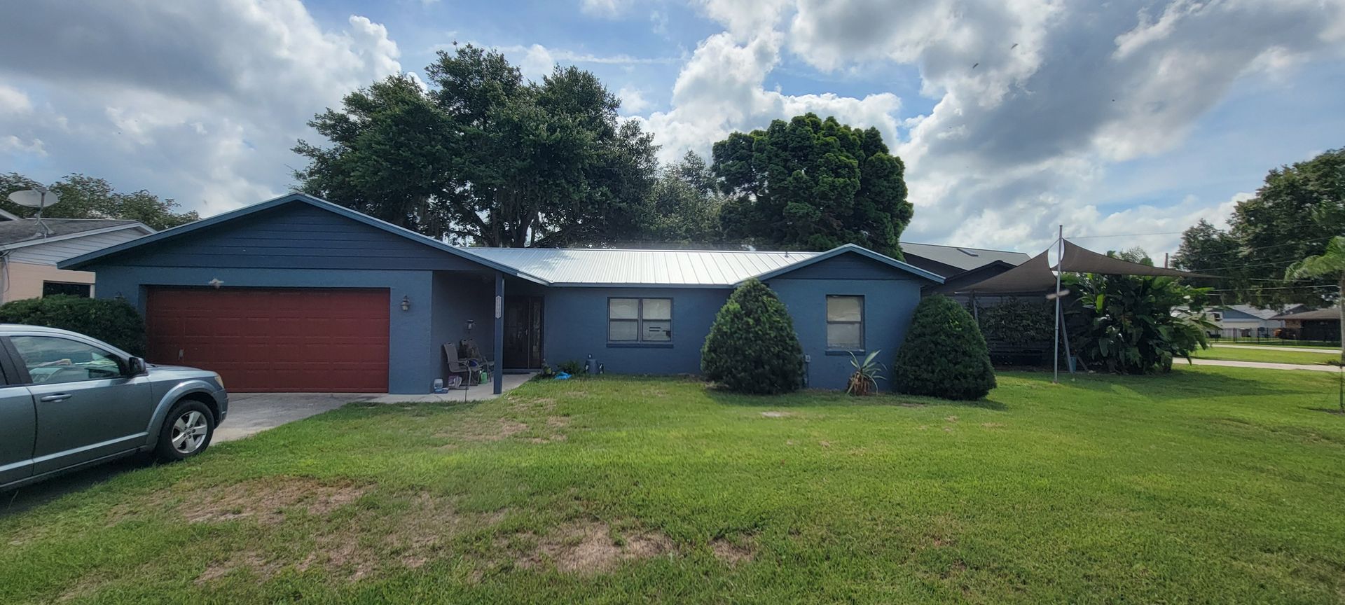 A blue house with a red garage door and a car parked in front of it.