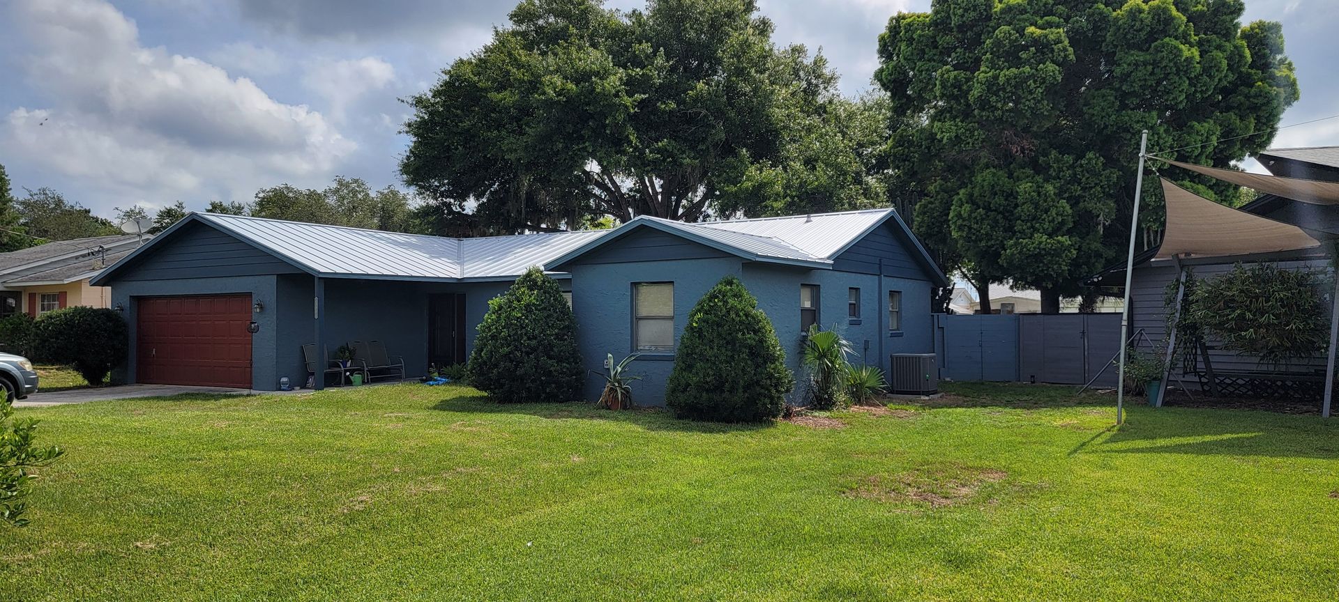 A blue house with a white roof is sitting on top of a lush green lawn.