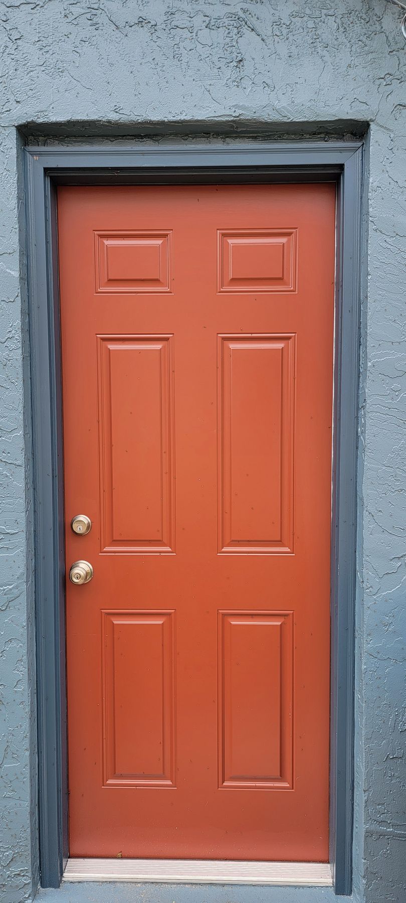 A red door is on a gray wall.
