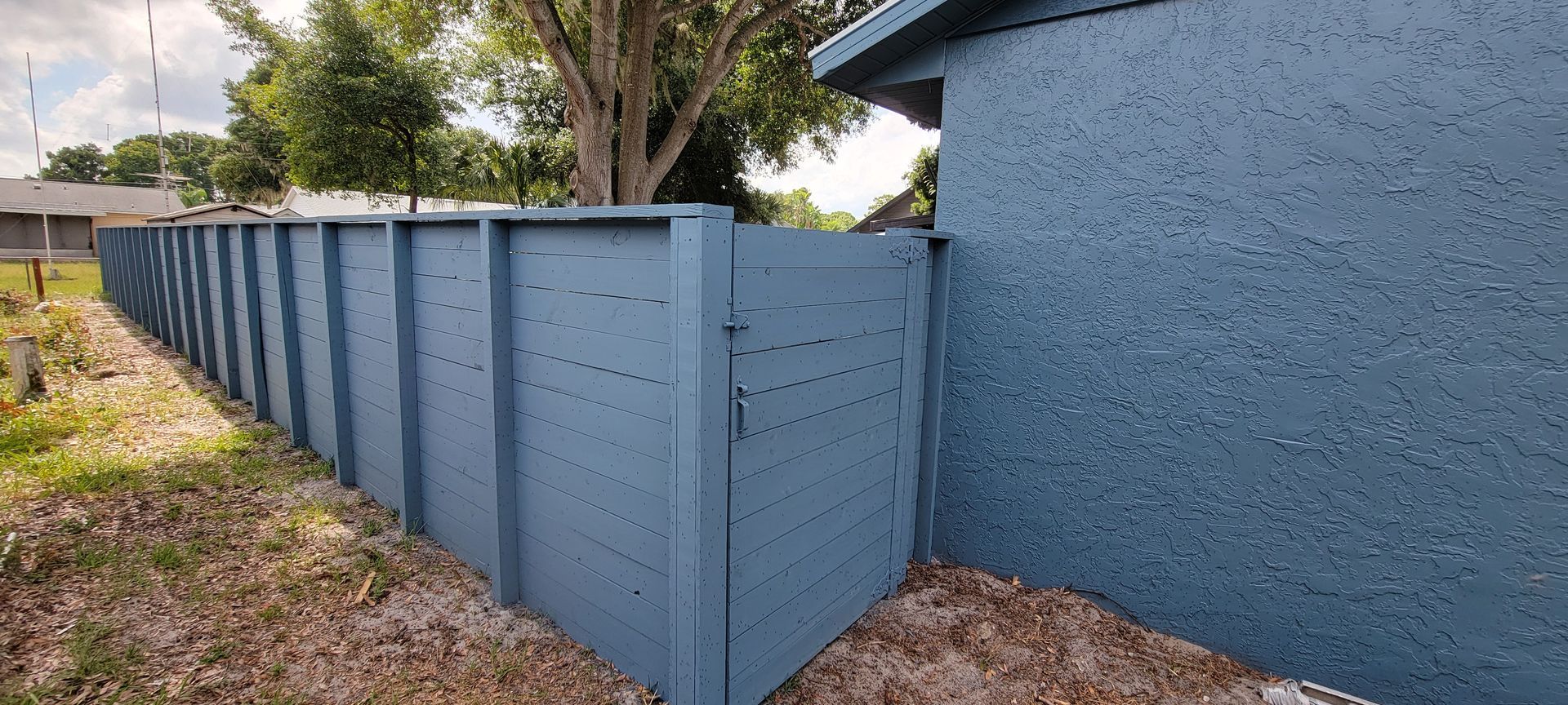 A blue fence is sitting next to a blue building.