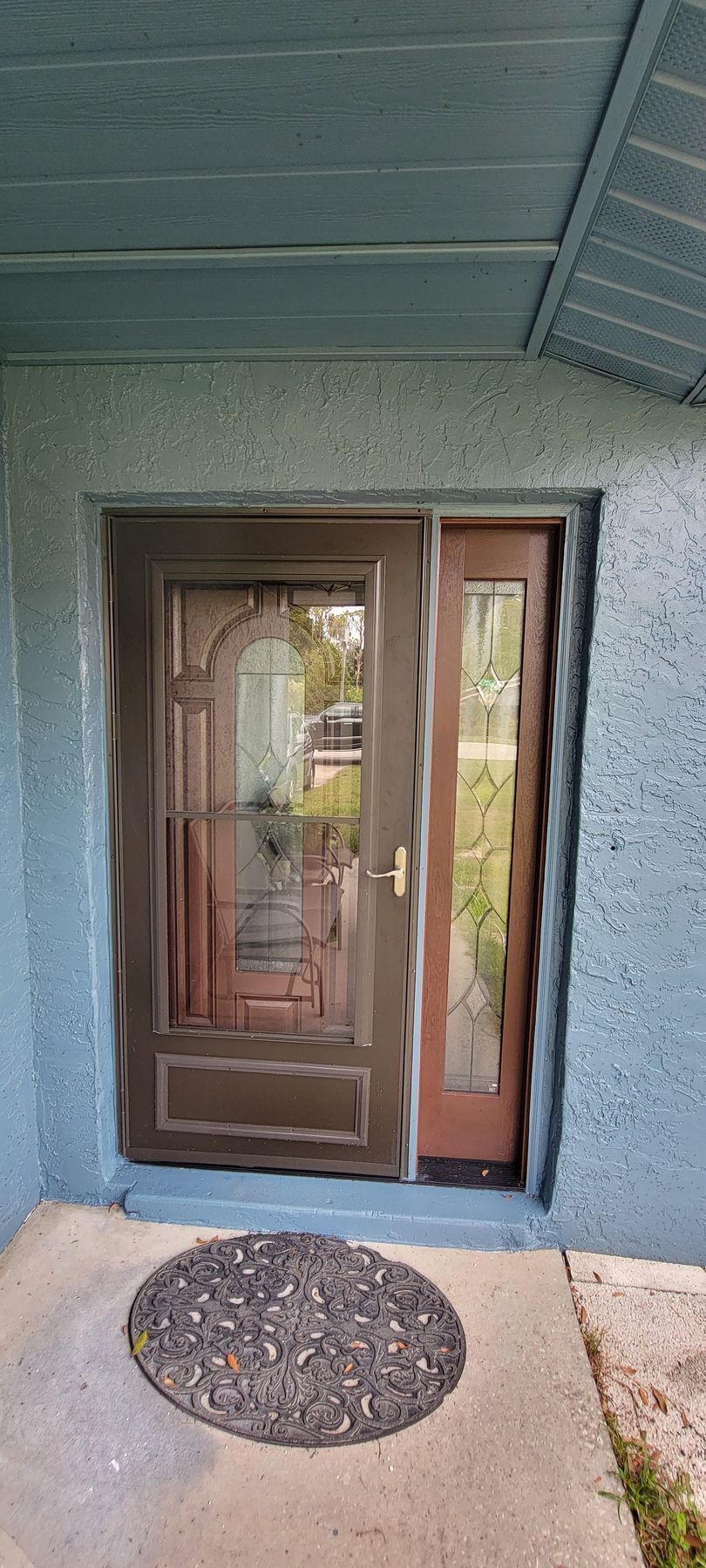 The front door of a house with a rug on the sidewalk.