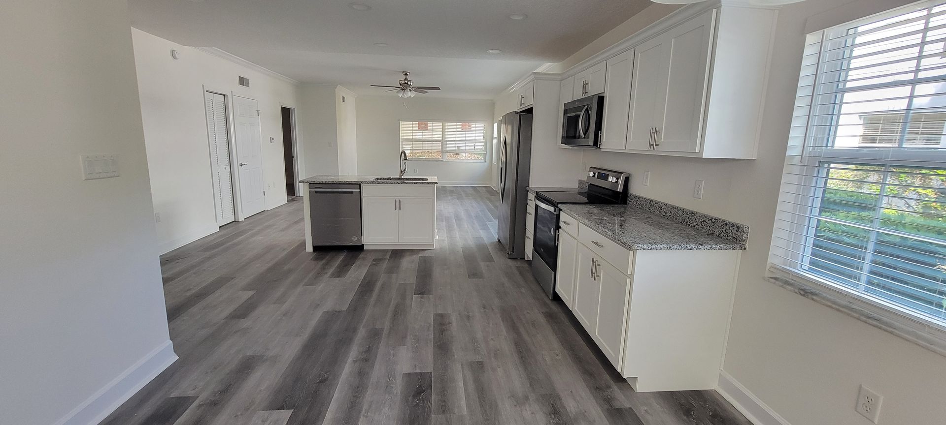 A kitchen with stainless steel appliances , granite counter tops , and hardwood floors.