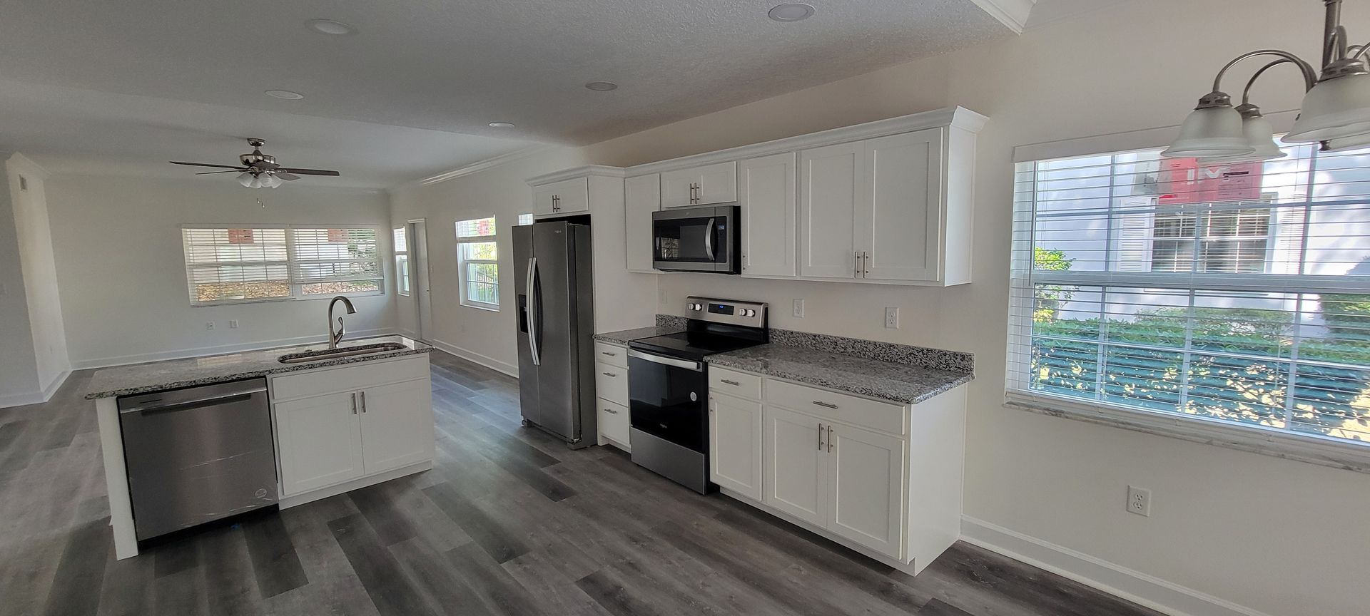 A kitchen with white cabinets , stainless steel appliances , granite counter tops and a large island.