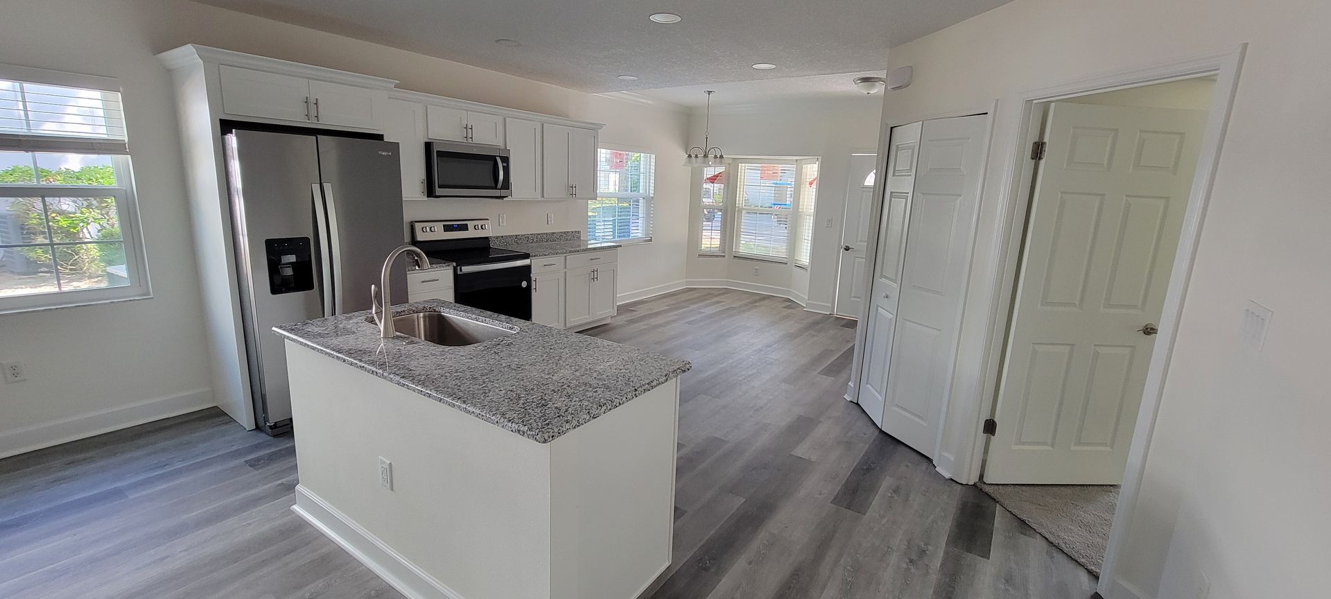 A kitchen with granite counter tops , stainless steel appliances , and white cabinets.