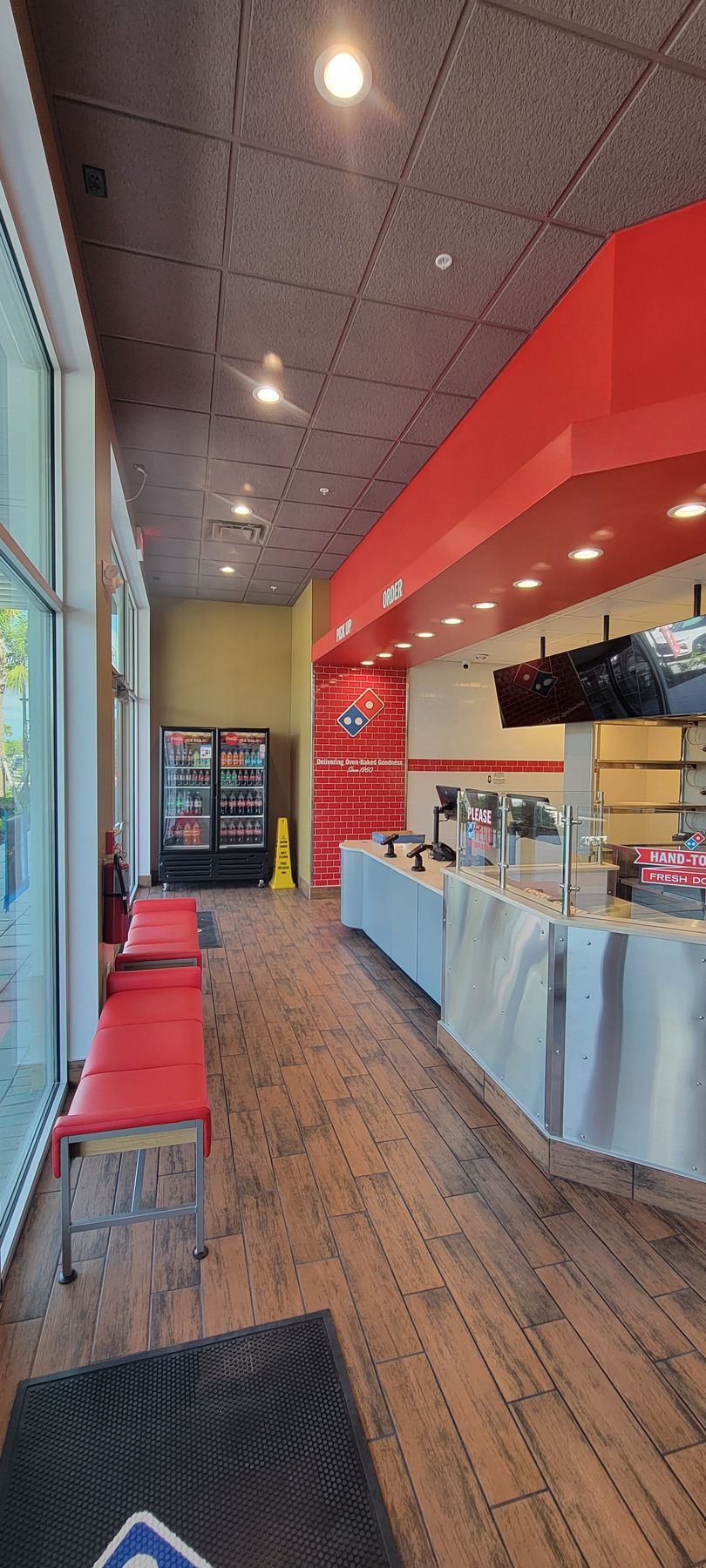 A long hallway in a pizza restaurant with tables and chairs.