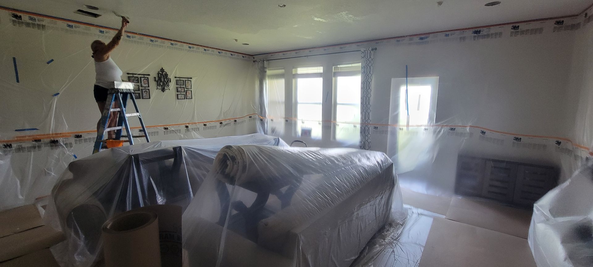 A man is painting the ceiling of a living room.