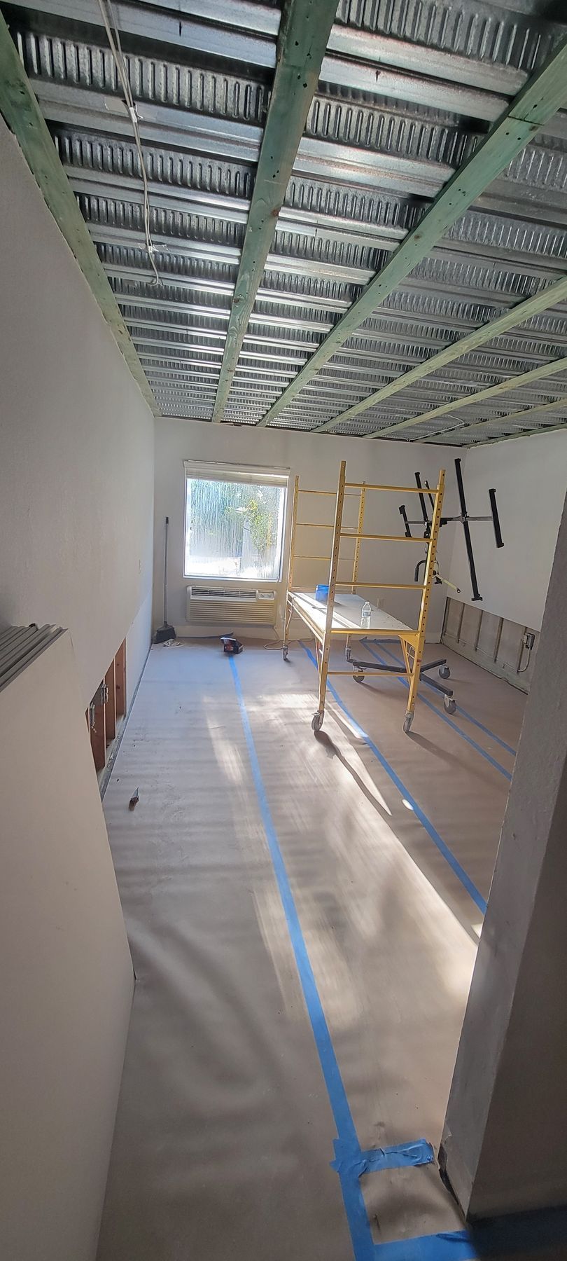 A room under construction with a scaffolding and a window.