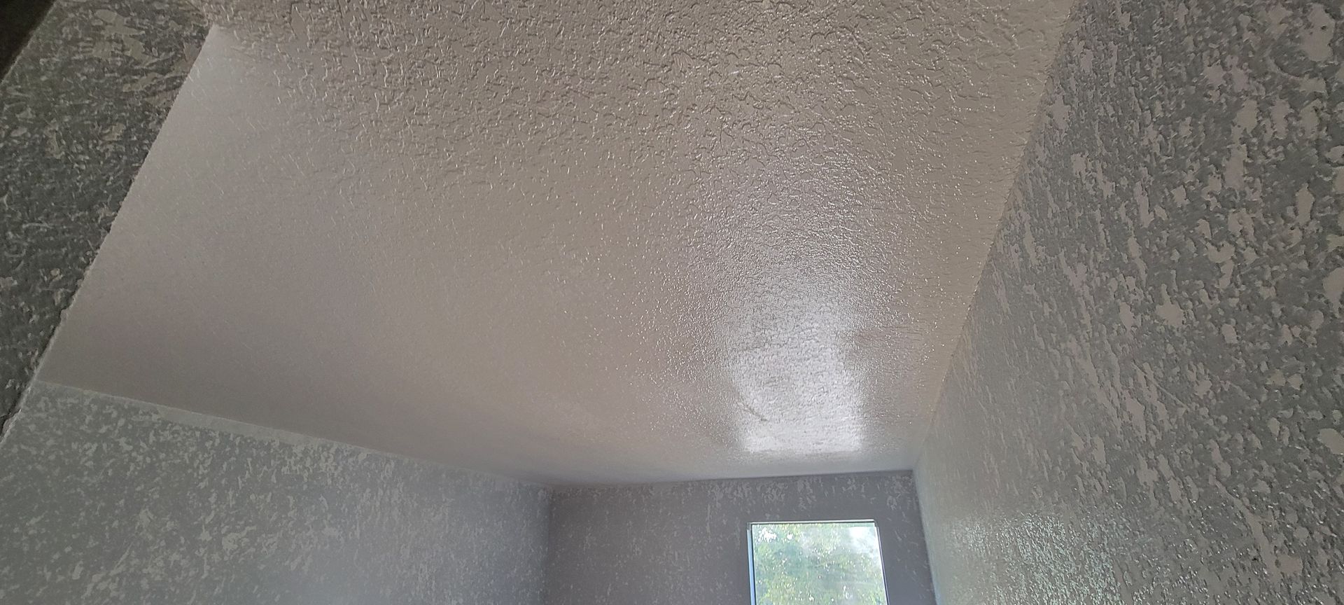 A room with a ceiling that is covered in glitter and a window.