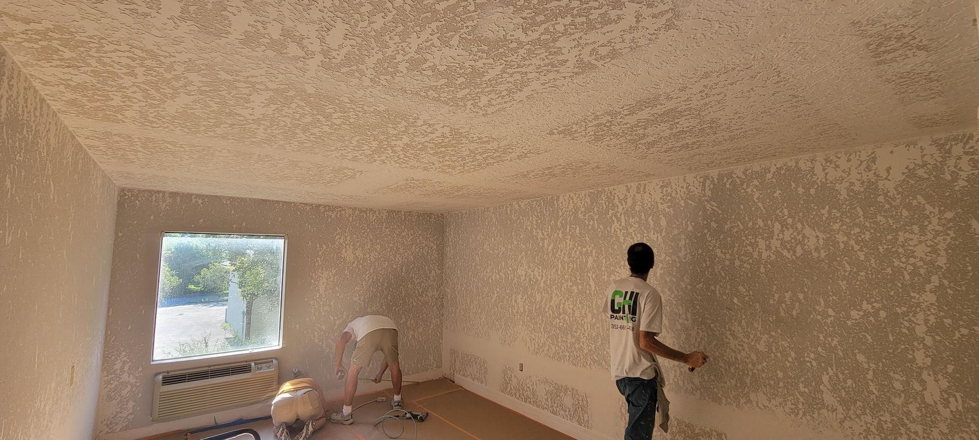 A man is painting the ceiling of a room.