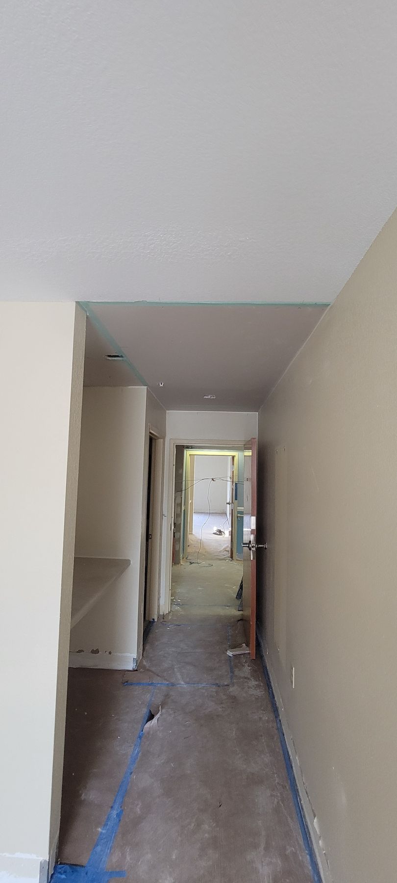 A long hallway with a ceiling that is being painted.