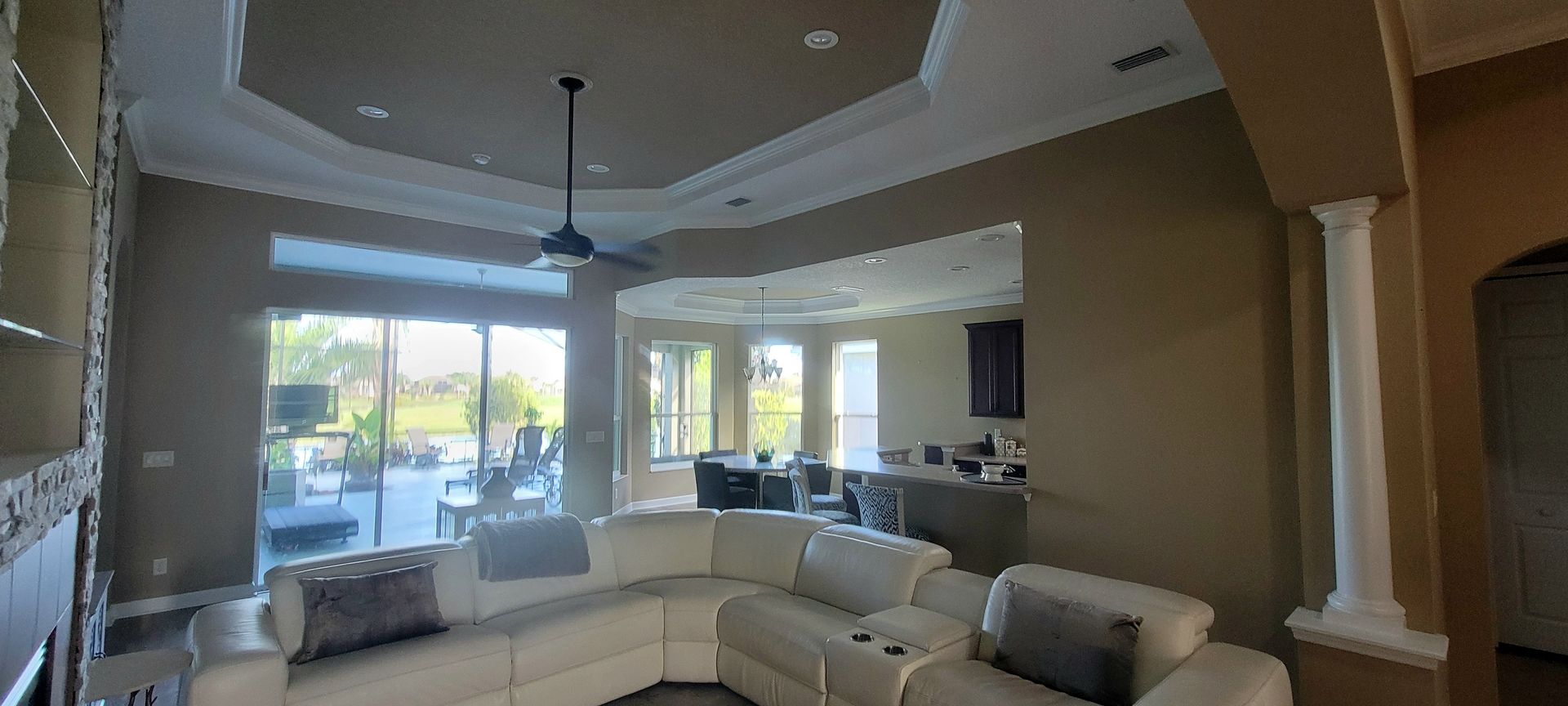 A living room with a sectional couch and a ceiling fan.