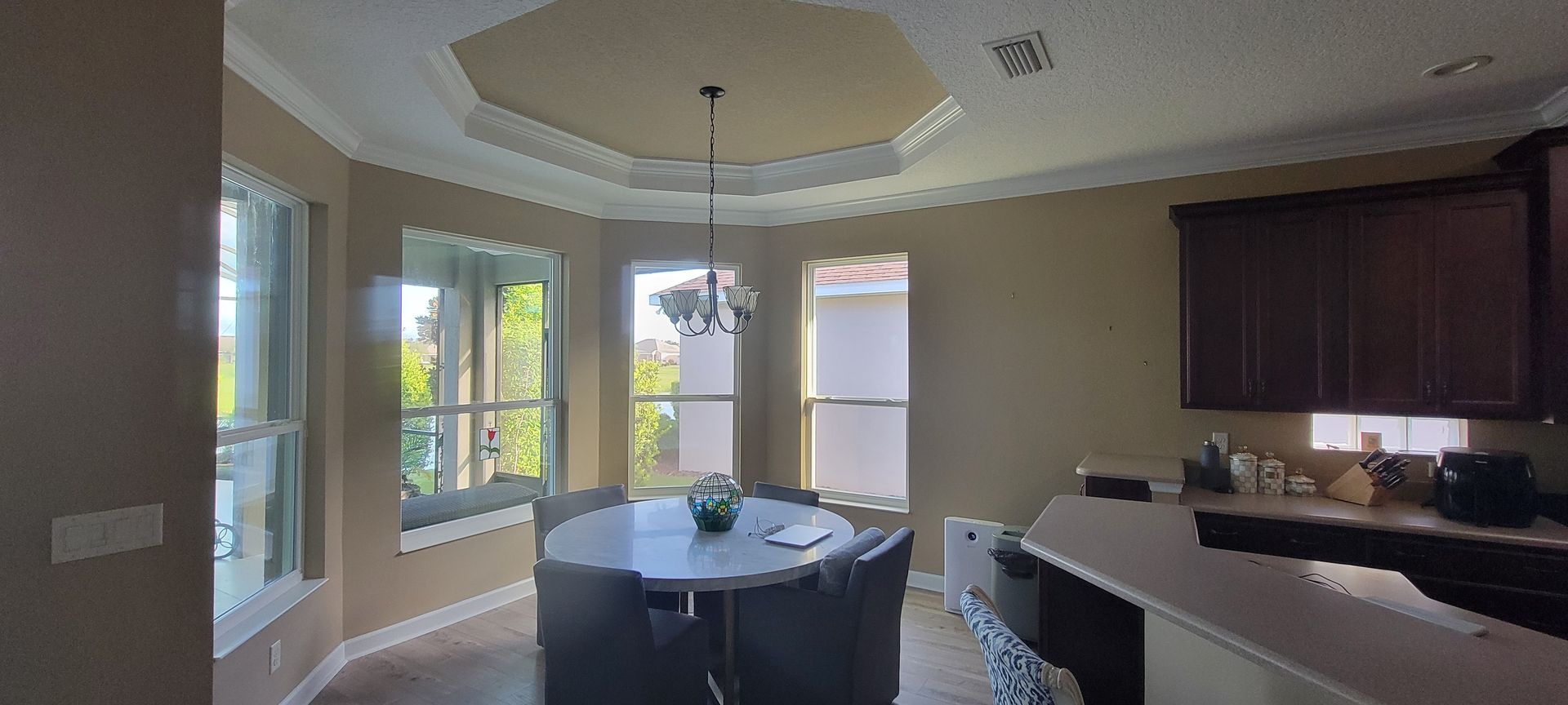 A dining room with a table and chairs and a kitchen in the background.