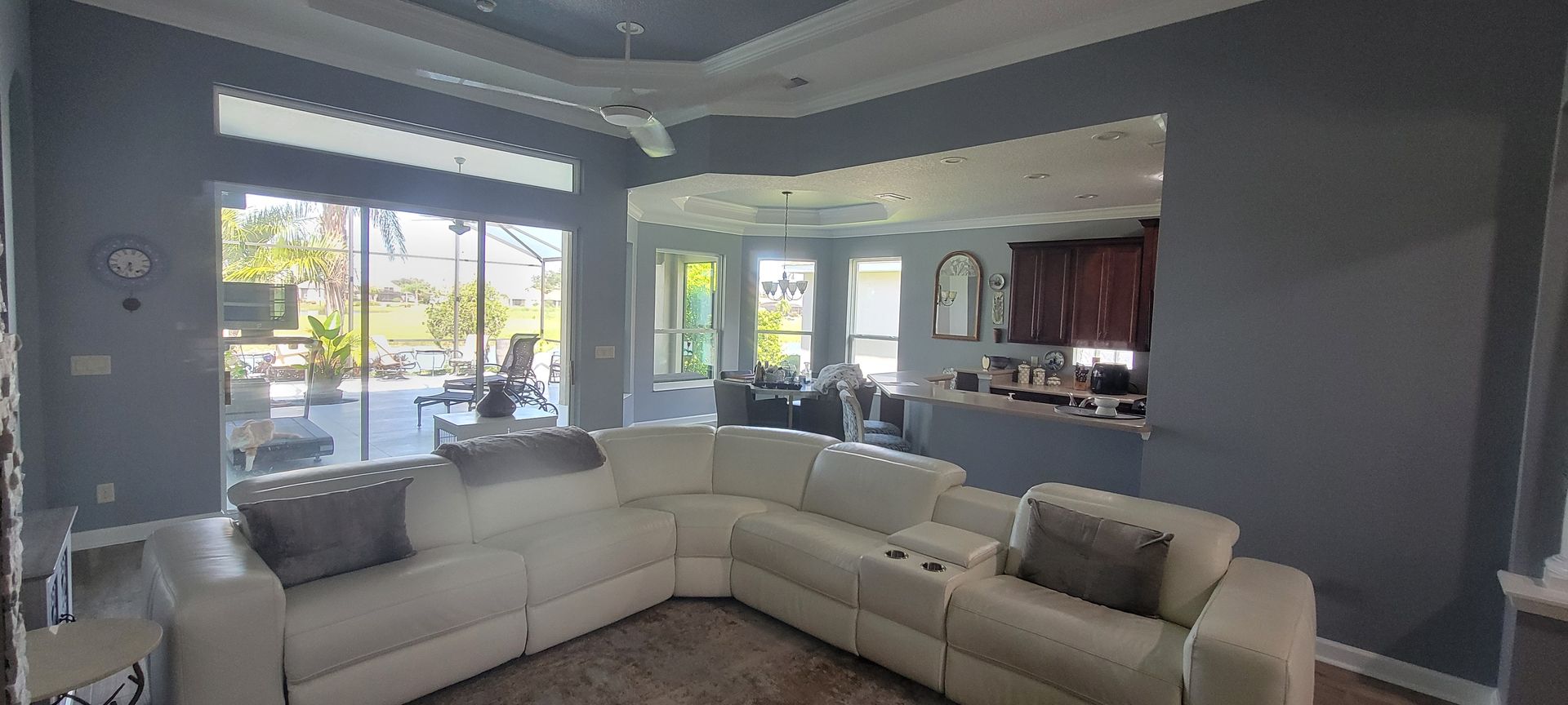 A living room with a large sectional couch and a ceiling fan.