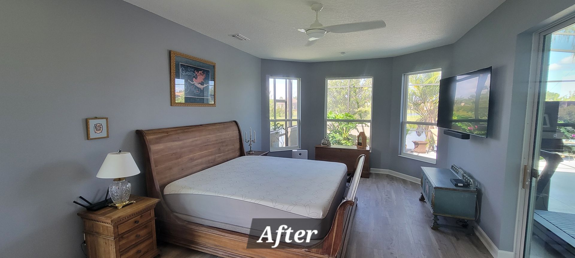 A bedroom with a large bed , nightstands , a television and a ceiling fan.