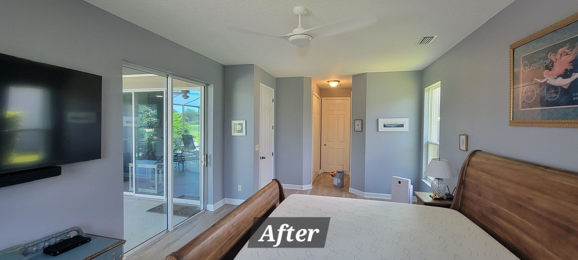 A bedroom with a bed , television , sliding glass doors and a ceiling fan.