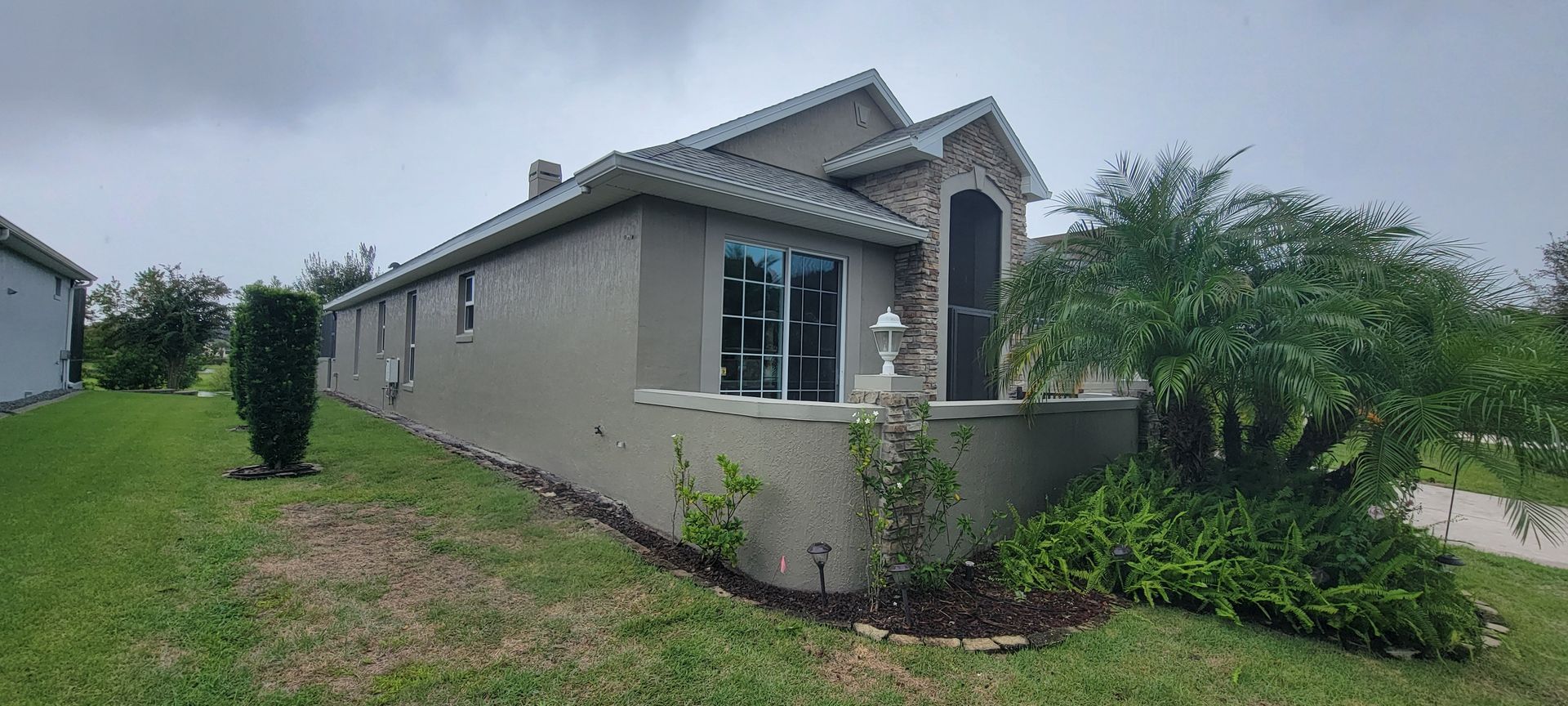A large house with a lot of windows is sitting on top of a lush green field.