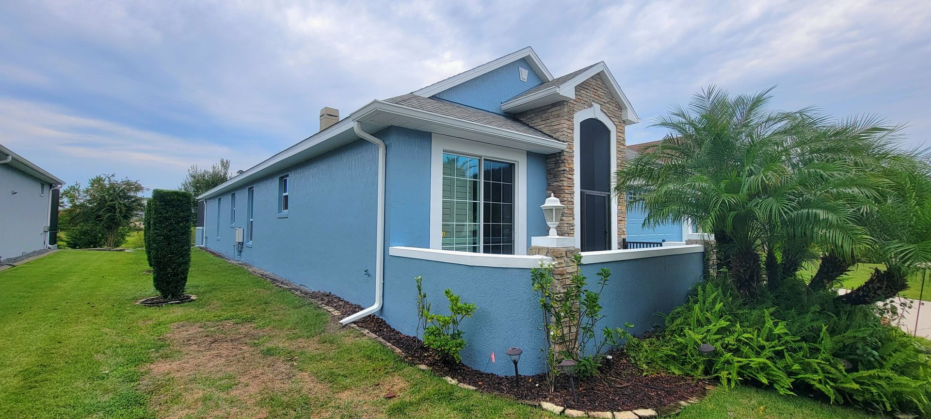 A blue house is sitting in the middle of a lush green field.