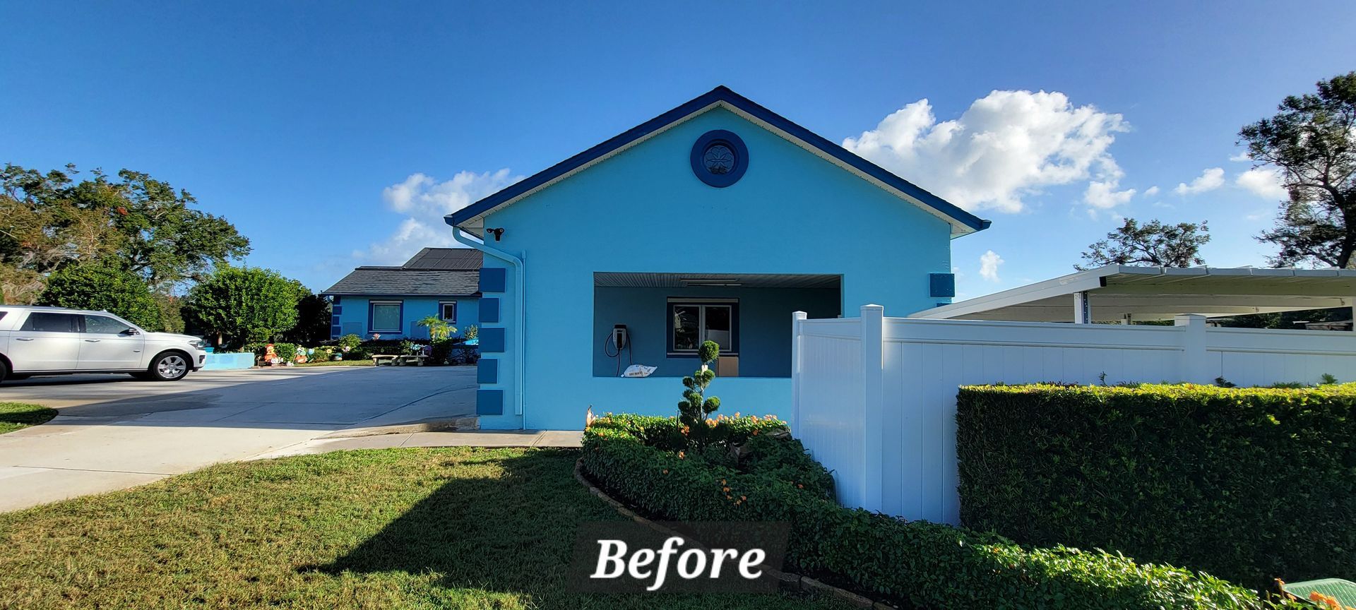 A before picture of a blue house with a white fence