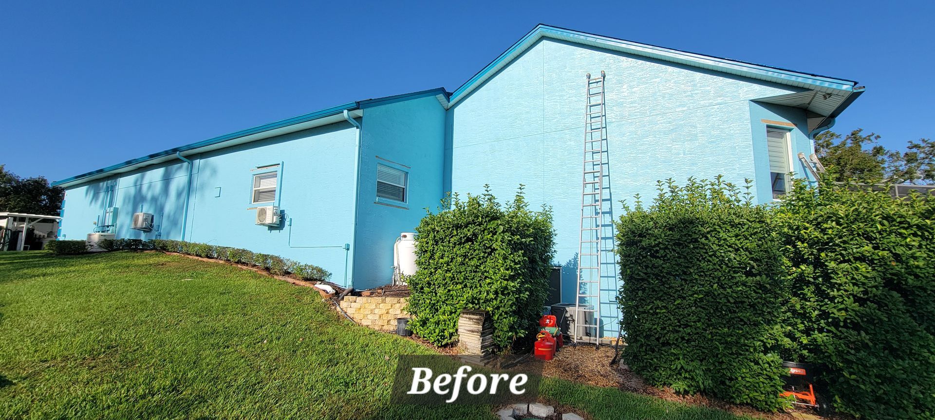 A blue house is sitting on top of a lush green hillside.