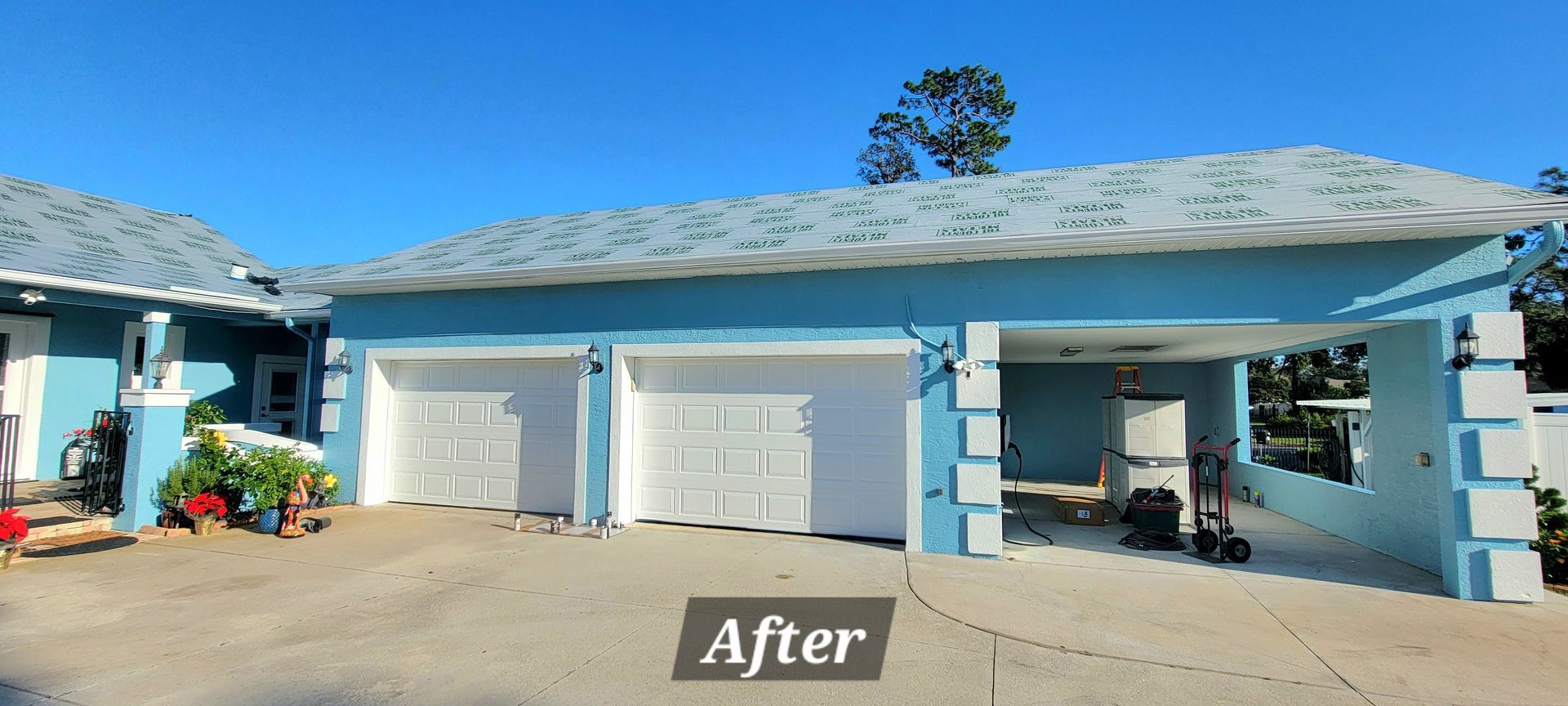 A blue house with white garage doors and a sign that says after