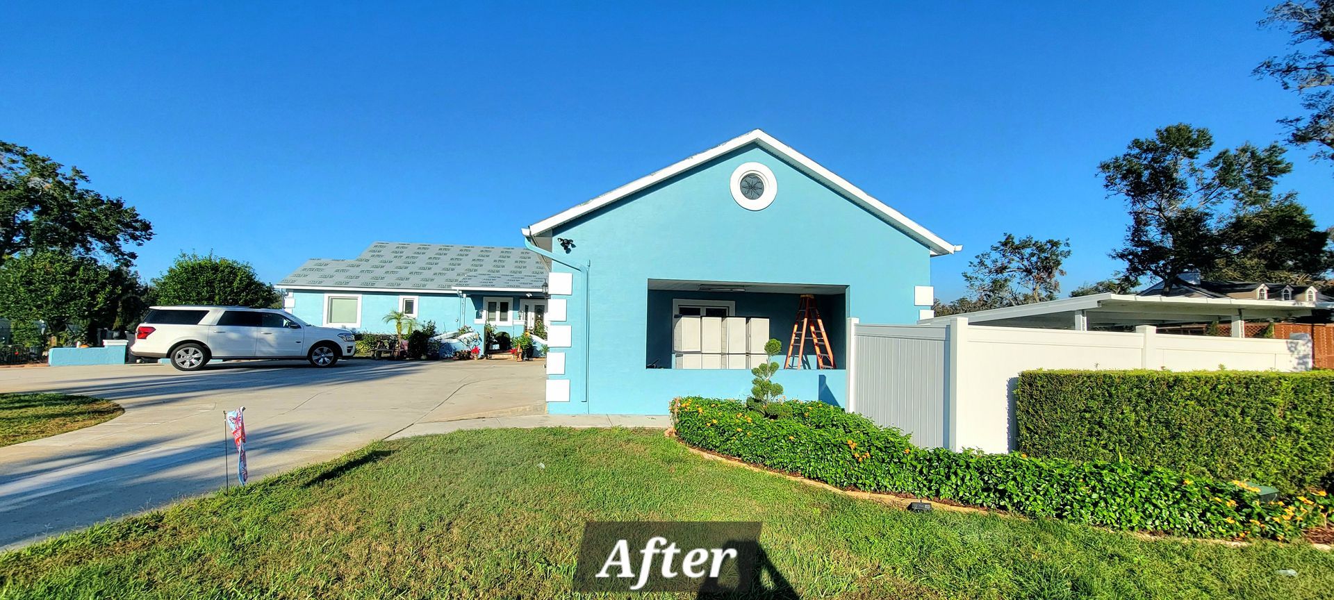 A blue house with a white car parked in front of it