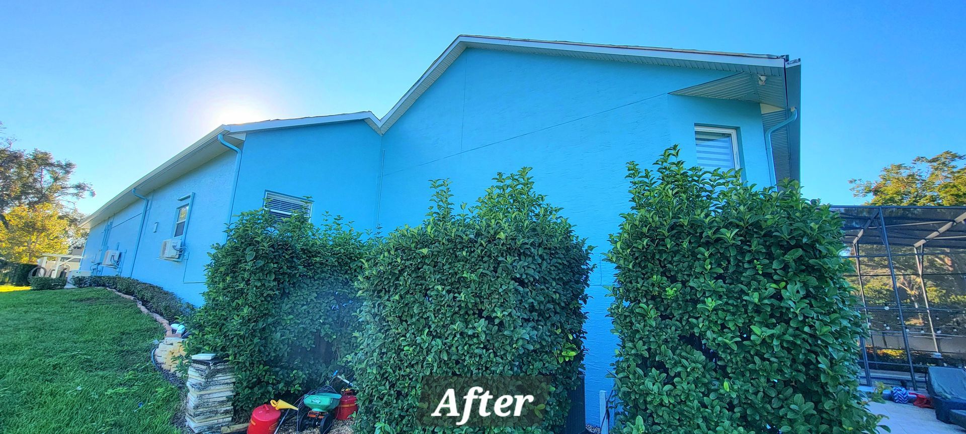 A blue house with a lawn mower in front of it.