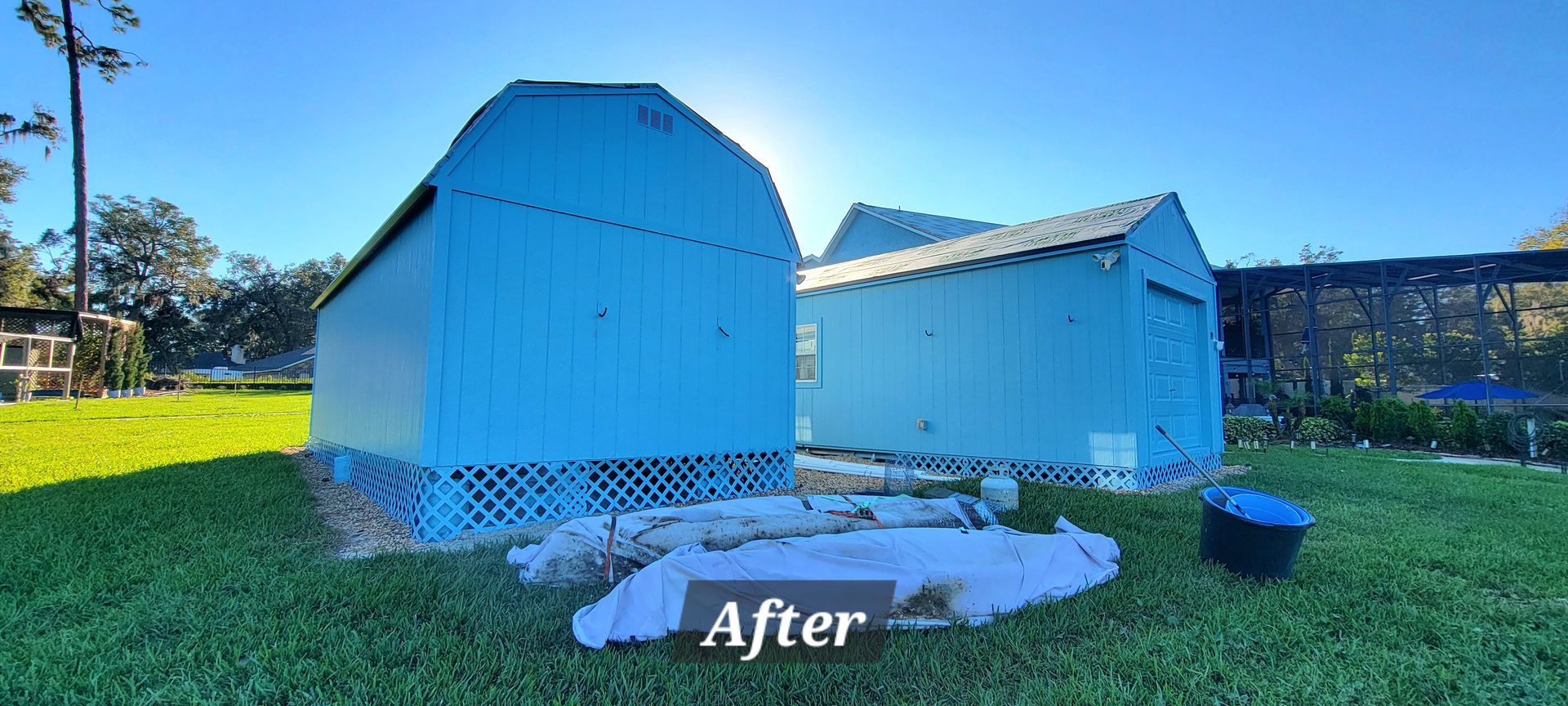 A couple of blue sheds are sitting on top of a lush green field.