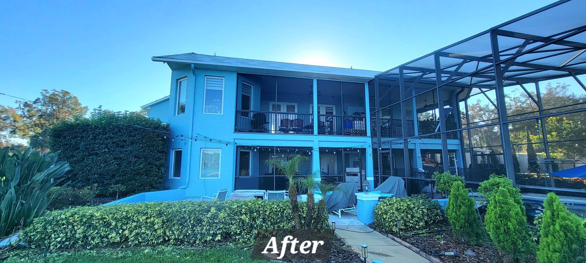 A blue house with a screened in porch and a blue sky in the background.