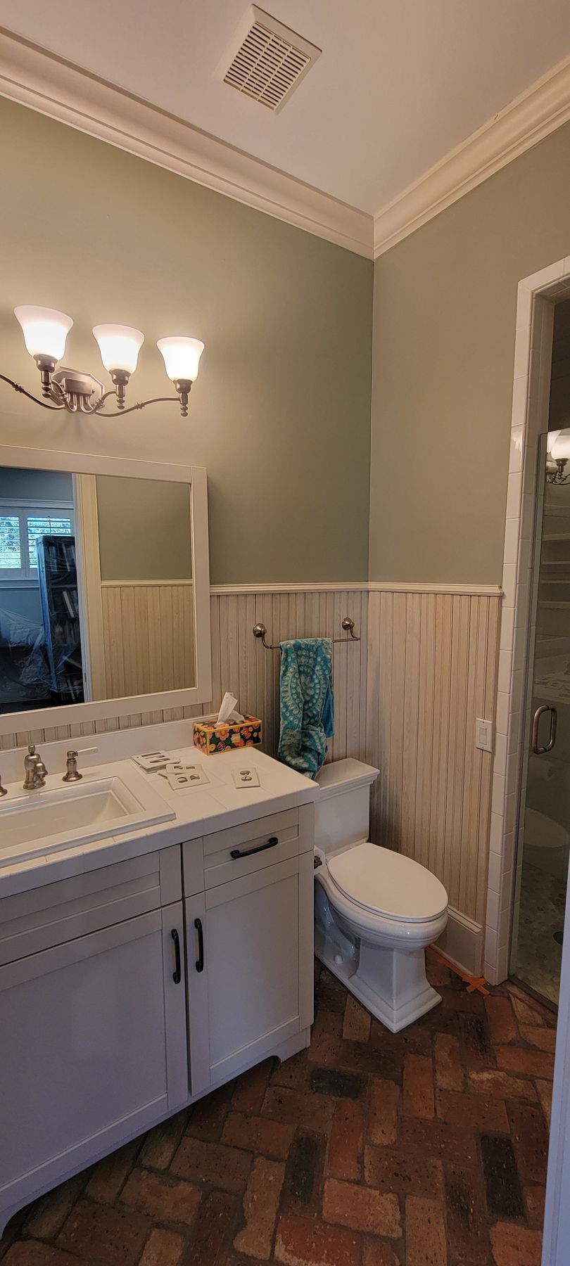 A bathroom with a toilet , sink and mirror.