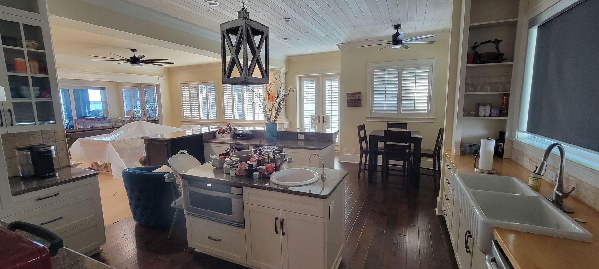 A kitchen with white cabinets , a sink , a table and chairs.